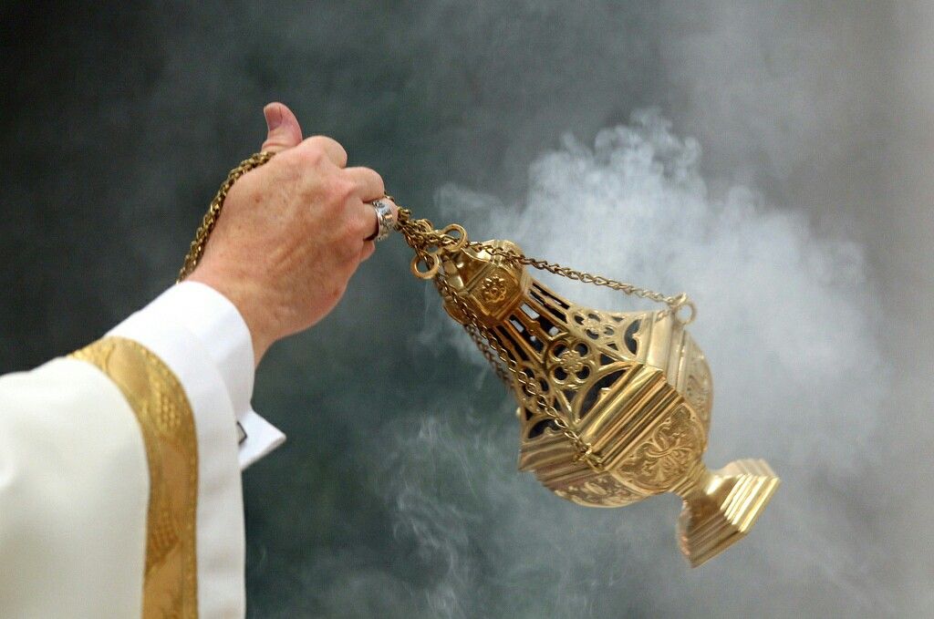 Catholic minister using a thurible with incense smoke