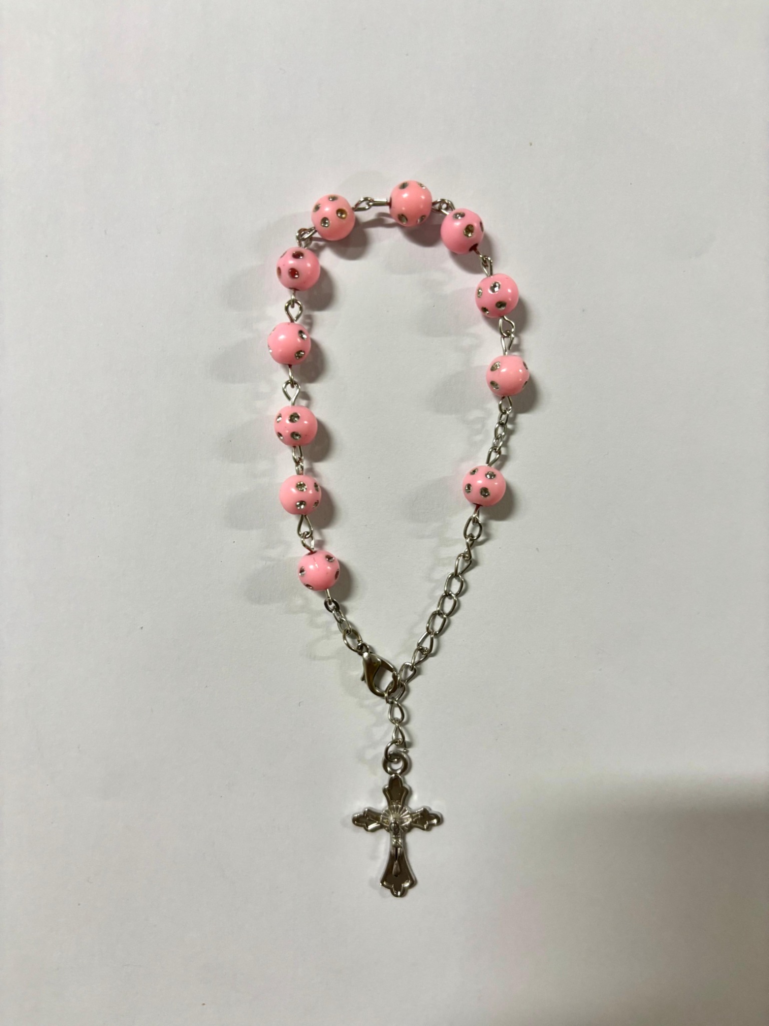 Pink bead rosary bracelet with silver-tone stud details and crucifix