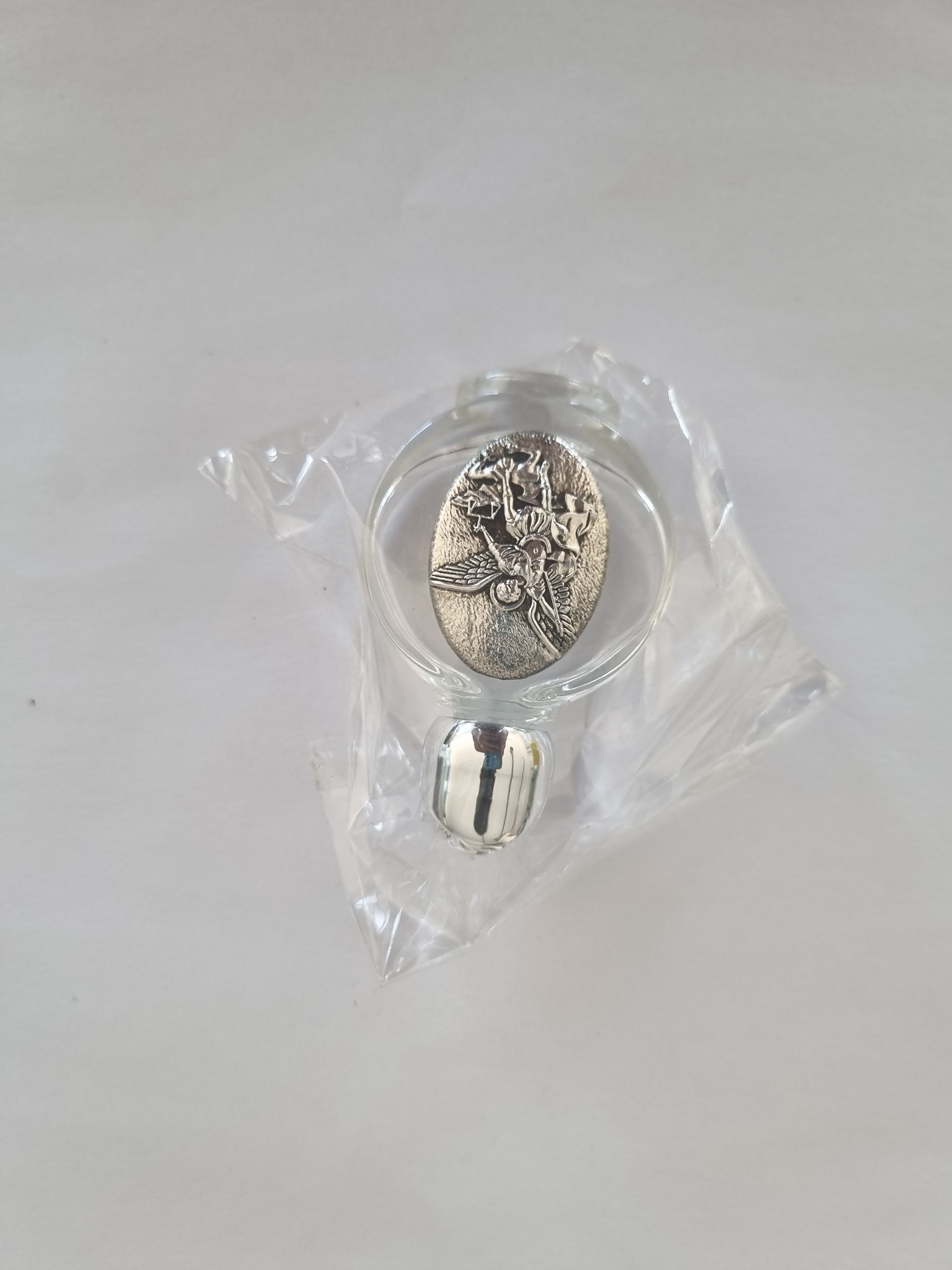 Round glass holy water bottle with silver-tone religious medallion